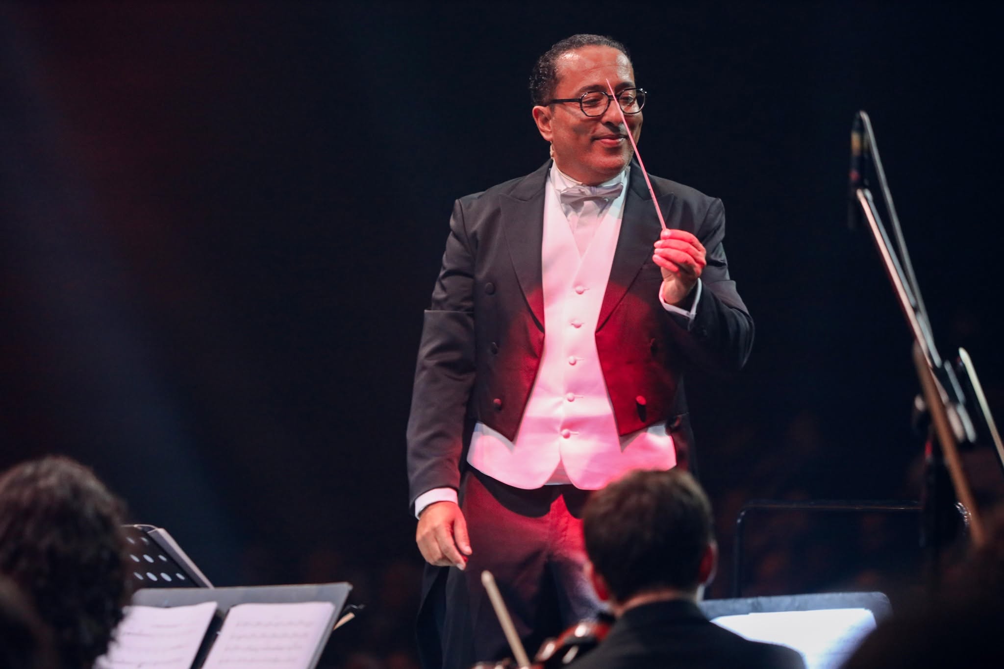 Adnane Matrone dirigeant un ensemble sur scene, en tenue de chef d'orchestre.